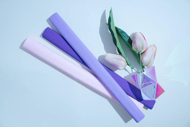 Barevné květiny v jasu váza a pastelově fialové krepové papíry na gradient modré pozadí s prázdným prostorem. Ležel. Příroda nebo láska koncept. - Fotografie, Obrázek