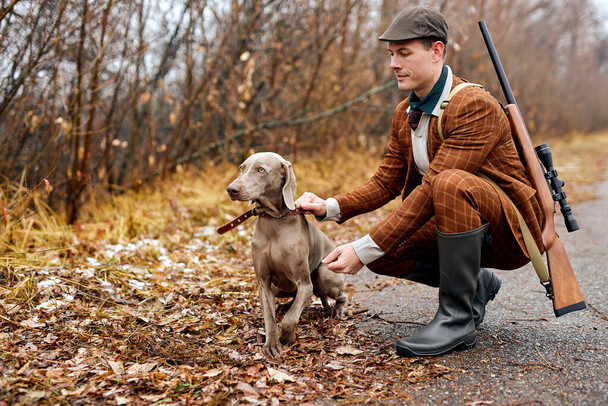 Stylish guy with dog breed weimaraner walks in the woods. Hunting dog training - Foto, Imagem