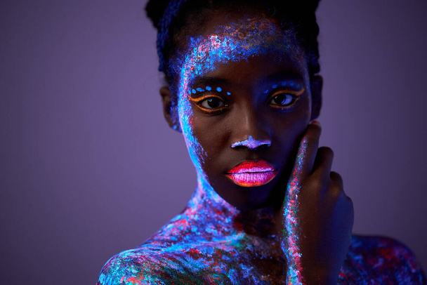 calm black model woman in neon light. black model with fluorescent make-up - Foto, afbeelding