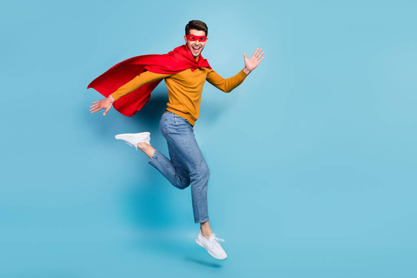 Photo of confident hurrying young man wear superman outfit smiling jumping running empty space isolated blue color background - Foto, afbeelding
