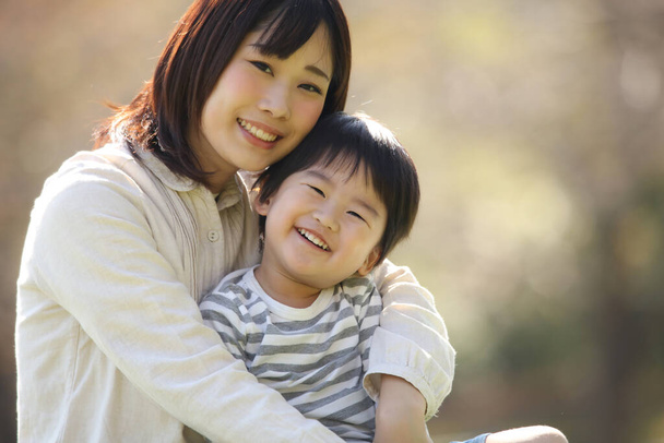 アジア系の母親が息子を抱きかかえて - 写真・画像