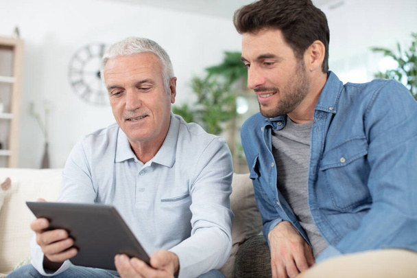 senior man using tablet pc with his adult son - Foto, imagen