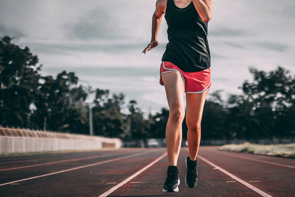 Nohy ženského běžce, který se silou šlápne na běžecké hřiště. Cvičení v létě s běžícími metodami, aby vaše tělo zdravé. - Fotografie, Obrázek