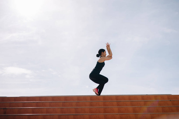 бегущая женщина растягивается во время утренних упражнений на лестнице стадиона концепции здравоохранения - Фото, изображение
