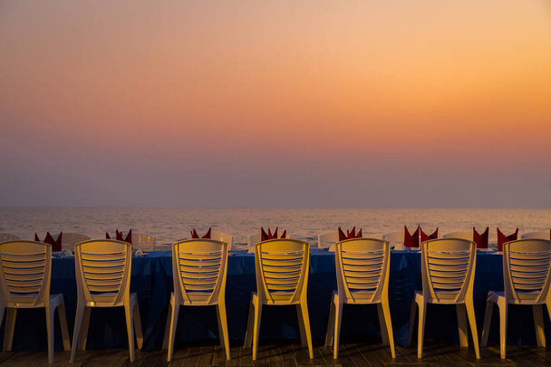 Обідній стіл на пляжі під час заходу сонця фону
 - Фото, зображення