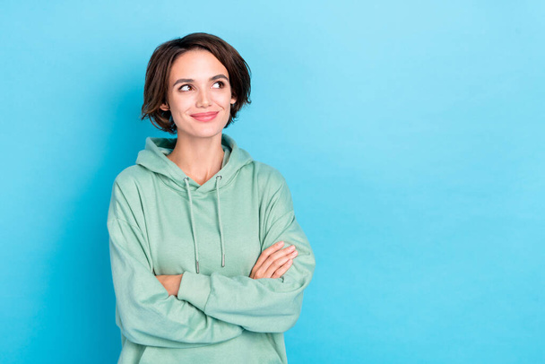 Photo of charming thoughtful lady dressed green pullover arms crossed empty space isolated blue color background - Photo, Image