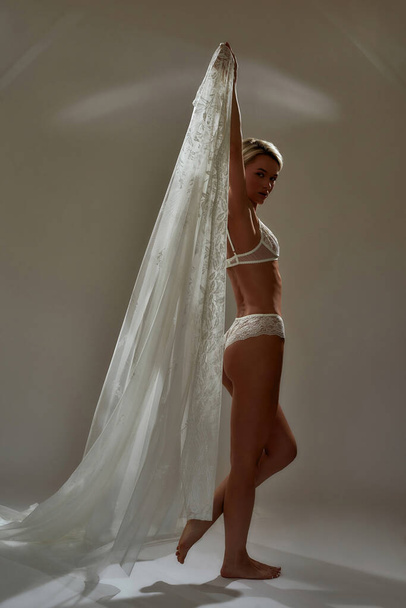 Blonde woman posing with white transparent fabric - Photo, image