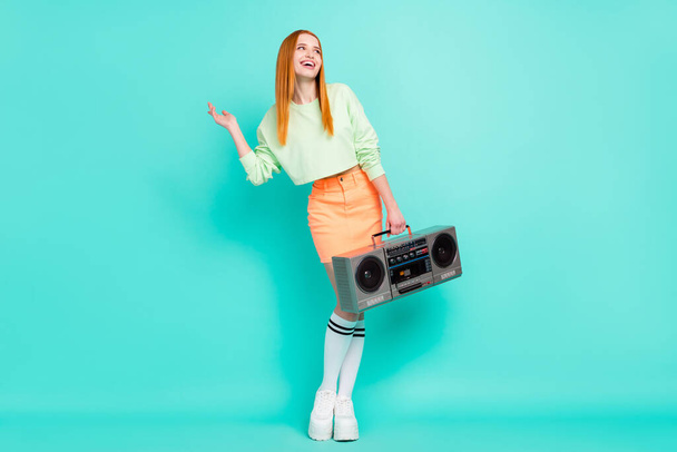 Full size photo of nice millennial lady hold boom box look empty space wear sport clothes skirt isolated on teal background - Foto, Imagen