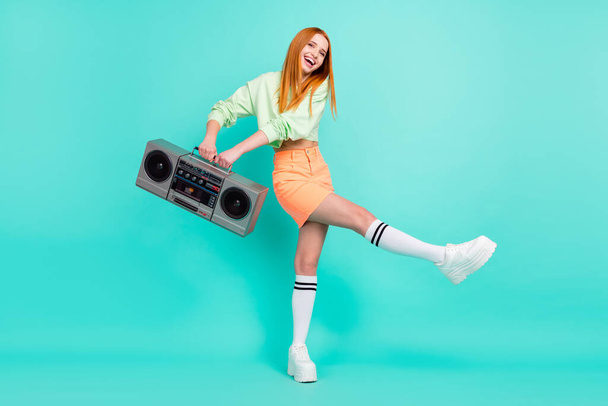 Full length body size photo pretty red haired girl dancing keeping retro tape recorder isolated vivid turquoise color background - Fotó, kép