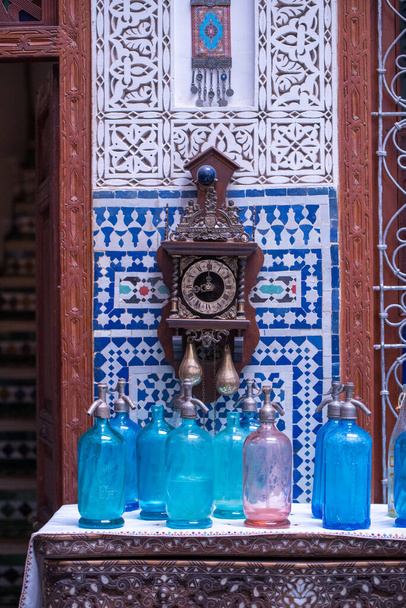 Wnętrze zbliżenie w riad w Marrakeszu Maroko z zegarem, niebieskie płytki i niebieskie butelki spray. - Zdjęcie, obraz