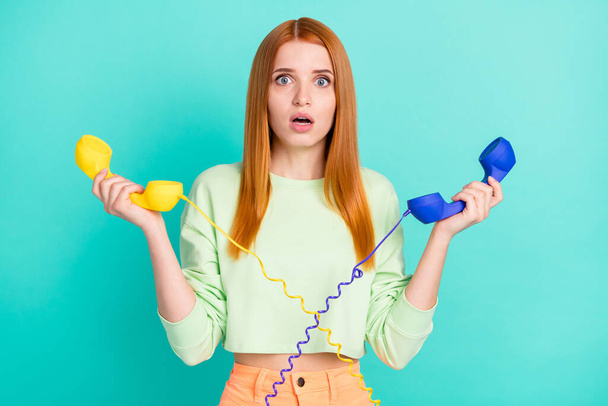 Photo of stressed millennial lady hold phones wear sport clothes isolated on vivid teal color background - Zdjęcie, obraz