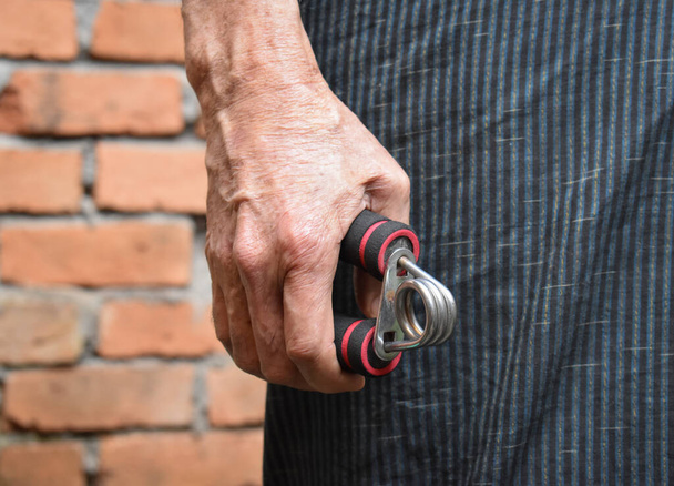 Hand of Southeast asian, Myanmar old man gripping hand exercise gripper. - Photo, Image