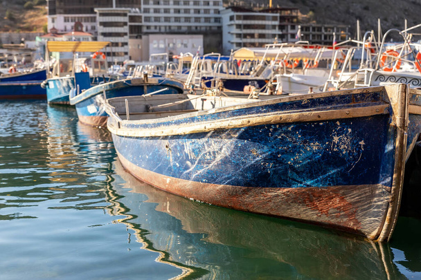 Κοντινό πλάνο λεπτομέρεια δείτε παλιά ξύλινα vintage πολύχρωμα φωτεινά αλιευτικά πλοία αγκυροβολημένα στη μαρίνα του χωριού ψαράδες καθαρά νερά κόλπο τη φωτεινή ηλιόλουστη μέρα. Θαλάσσιο λιμάνι με παραδοσιακά ρετρό σκάφη - Φωτογραφία, εικόνα