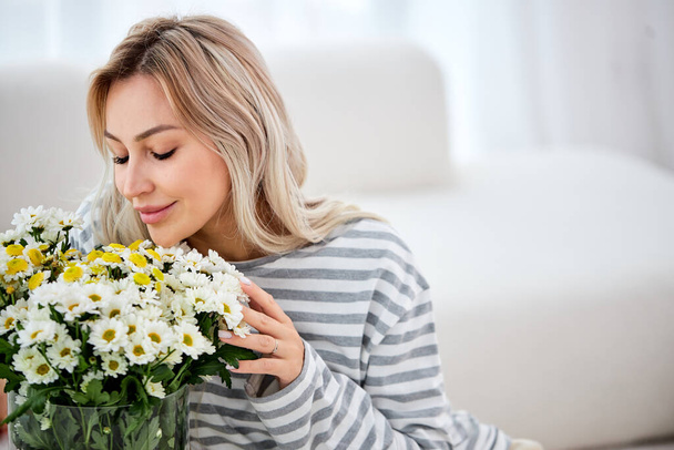 Carefree stylish woman ordered flowers for home, close eyes smiling,sniffing - Foto, immagini