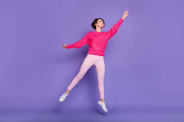 Full body photo of young excited girl happy positive smile jump up try catch umbrella isolated over purple color background - Fotó, kép