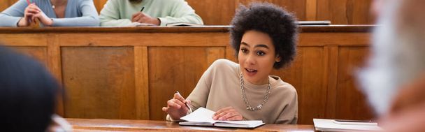 Studente afroamericano con taccuino che parla con professore sfocato all'università, striscione  - Foto, immagini