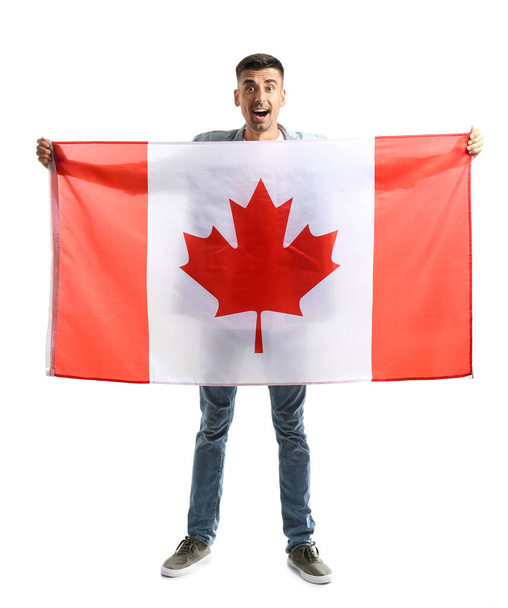 Ευτυχισμένος νεαρός άνδρας με καναδική σημαία απομονωμένος σε λευκό - Φωτογραφία, εικόνα