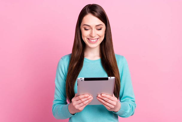 Portrait of attractive focused cheerful girl holding in hands ebook researching web isolated over pink pastel color background - Фото, изображение