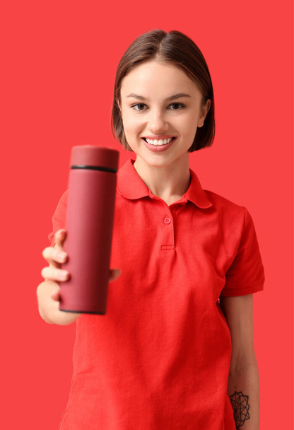 Beautiful young woman with thermos on color background - Foto, Imagem