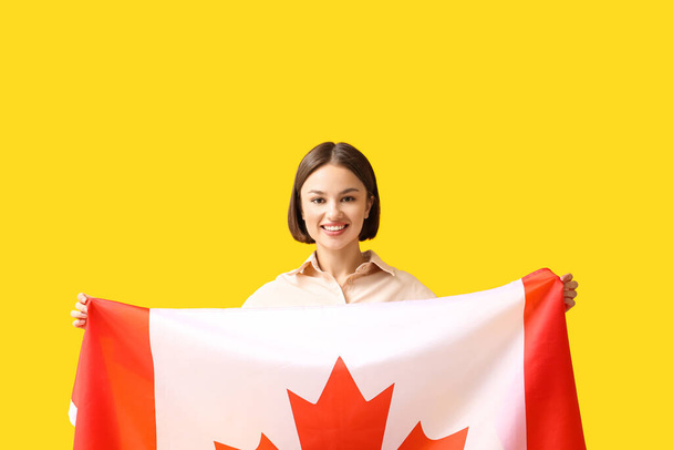 Piękna młoda kobieta z kanadyjską flagą na żółtym tle - Zdjęcie, obraz