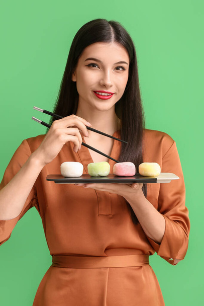 Beautiful young woman with tasty Japanese mochi on color background - Foto, Imagen