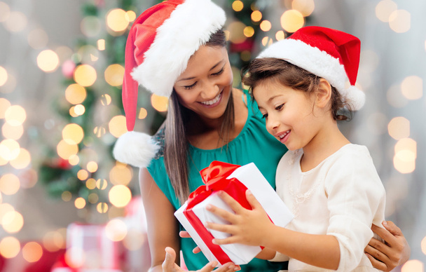 happy mother and girl in santa hats with gift box - Foto, Imagen