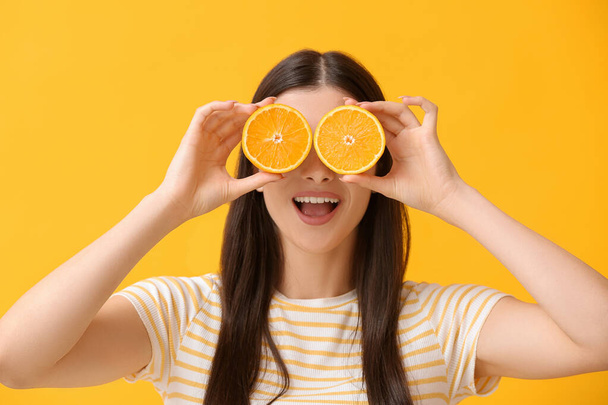 Funny young woman with orange on color background - Foto, Imagem