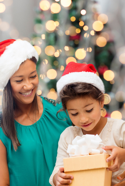 happy mother and girl in santa hats with gift box - Foto, Imagem