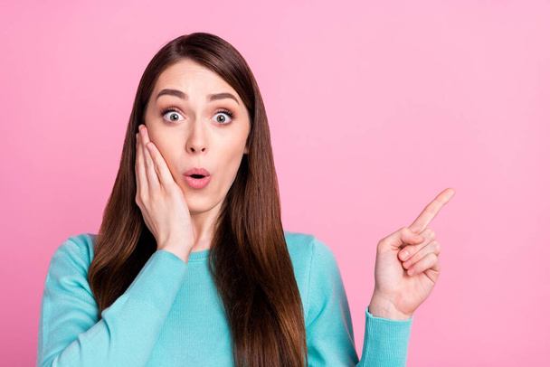 Photo of impressed funny young woman wear blue sweater arm cheek pointing finger empty space isolated pink color background - 写真・画像