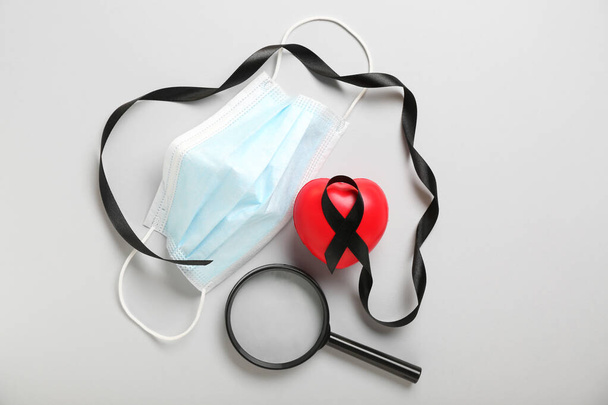 Black ribbon, medical mask, magnifier and heart on grey background. Melanoma concept - Valokuva, kuva