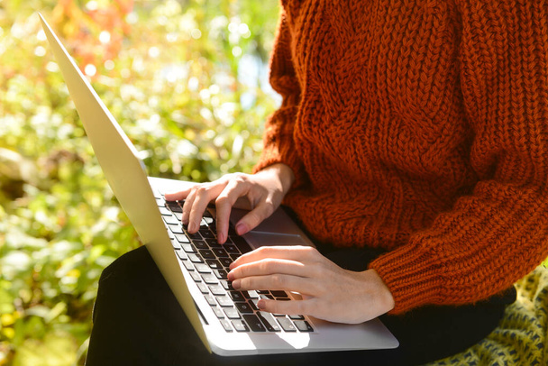 jong meisje werken op laptop in de buurt van meer in park - Foto, afbeelding