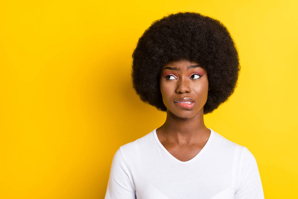 Photo of unhappy troubled young dark skin woman look empty space bite lip isolated on yellow color background - Photo, Image