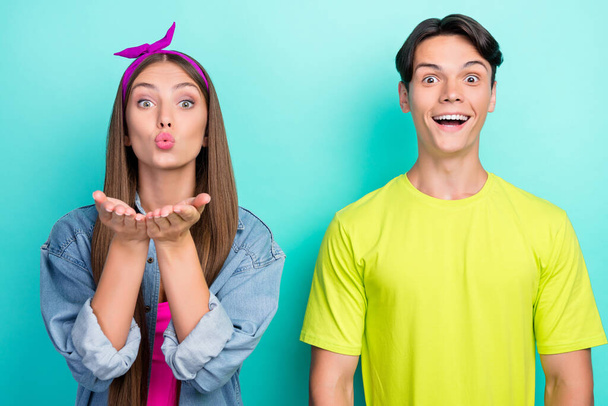 Photo of cute brunette millennial couple blow kiss wear yellow pink t-shirts jeans isolated on teal color background - Foto, afbeelding