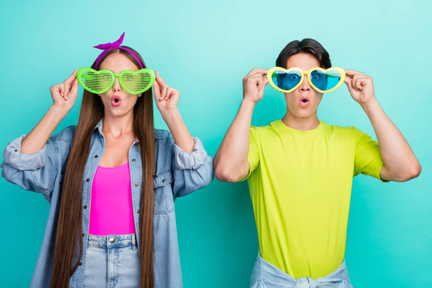 Photo of playful brunette young couple try eyewear wear colorful t-shirts isolated on teal color background - Photo, Image