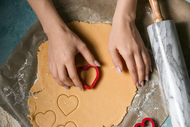 Woman preparing tasty heart shaped cookies at table. Valentines Day celebration - Zdjęcie, obraz