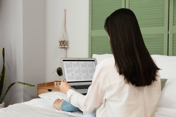 Vrouw met kalender op laptop in slaapkamer - Foto, afbeelding