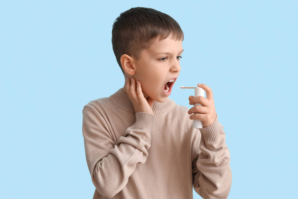 Niño enfermo con inhalador sobre fondo azul - Foto, Imagen
