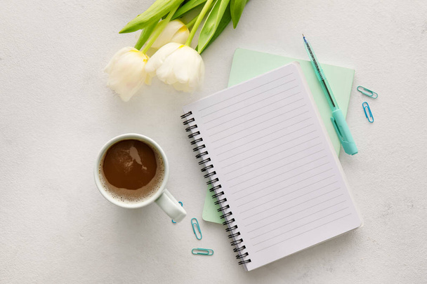 Σύνθεση με notebook, φλιτζάνι καφέ και τουλίπες σε ελαφρύ φόντο - Φωτογραφία, εικόνα