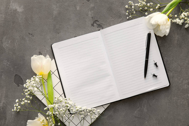Komposition mit leerem Notizbuch, Stift und schönen Blumen auf Grunge-Hintergrund - Foto, Bild