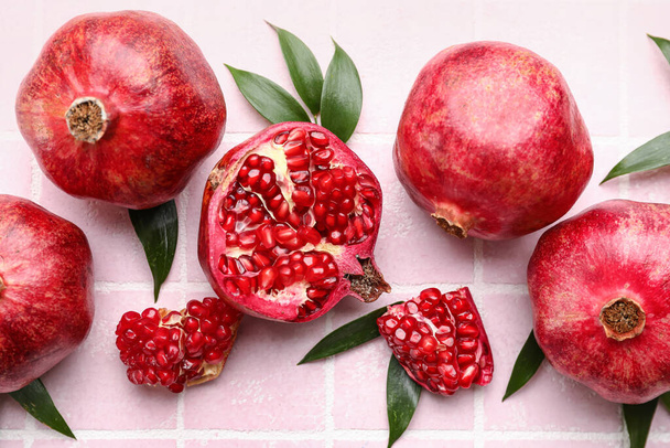 Delicious pomegranates on pink tile background - Фото, изображение