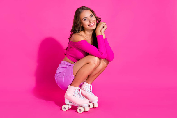 Full size photo of cheerful adorable lady squat beaming smile look camera isolated on bright pink color background - Фото, изображение