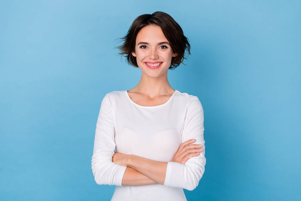 Photo adorable positive businesswoman with folded hands wear white color apparel isolated on blue color background - 写真・画像