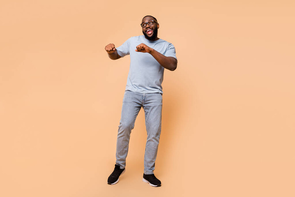Full length body size view of attractive cheerful guy moving having fun good mood isolated over beige pastel color background - Фото, изображение