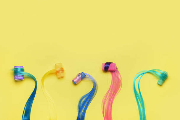 Různé barevné prameny vlasů s natáčkami na žlutém pozadí - Fotografie, Obrázek