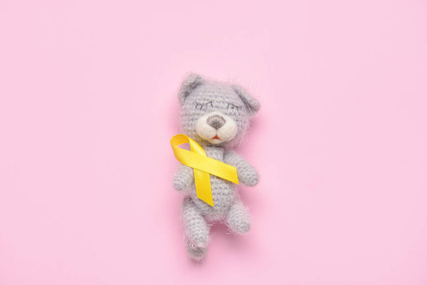 Golden awareness ribbon and toy bear on color background. International Childhood Cancer Day - Photo, Image