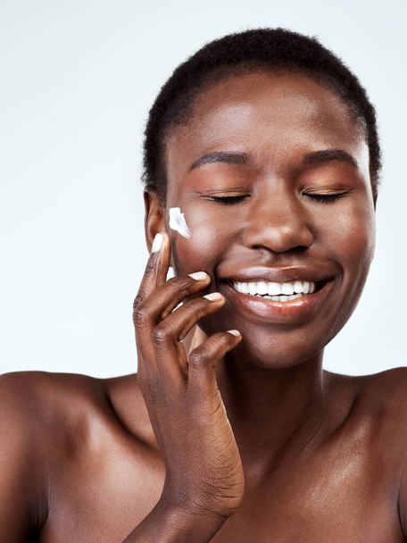 So luxurious on her skin. Studio shot of a beautiful young woman applying moisturiser against a grey background. - Φωτογραφία, εικόνα