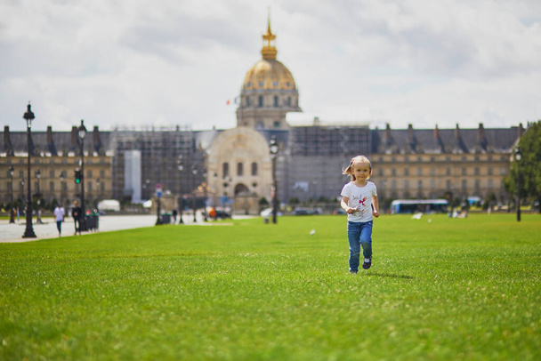 Happy cheerful toddler girl having fun on a street of Paris, near Les Invalides. Summer in France with kids - Foto, Bild