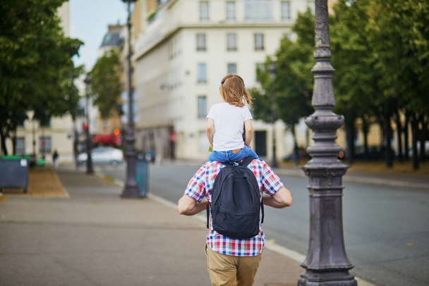 Father holding his daughter on shoulders and walking on a street of Paris, France - Valokuva, kuva
