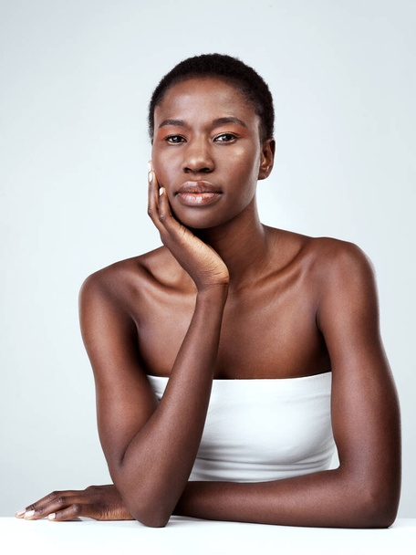 Healthy skin enhances her beauty. Studio portrait of a beautiful young woman feeling her skin against a grey background. - Fotó, kép