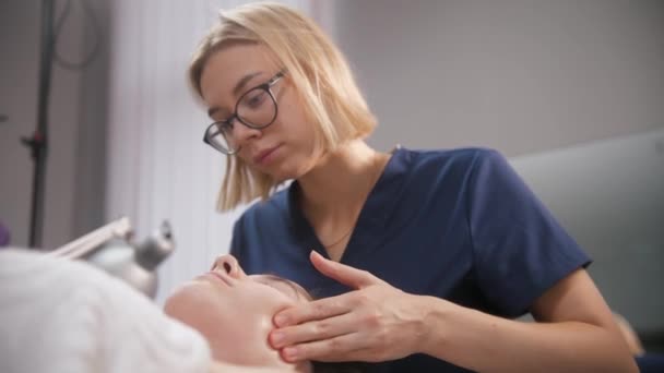 Séance de massage - jeune femme blonde massant le visage de sa cliente - Séquence, vidéo